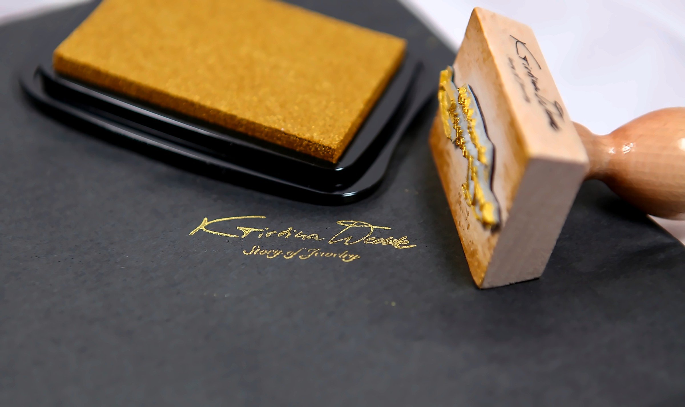 Kristina Wedde’s gold signature stamp and ink pad on black paper