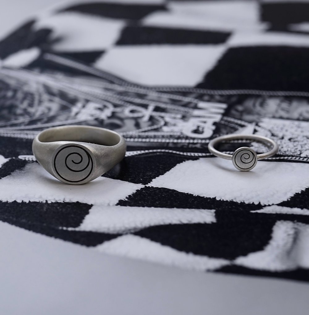 Two signet rings with a spiral motif on a black and white checkered cloth