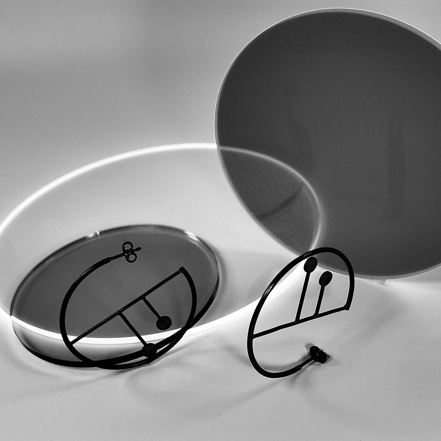 Black wire hoop earrings with a drawn line and two dots, black and white photo
