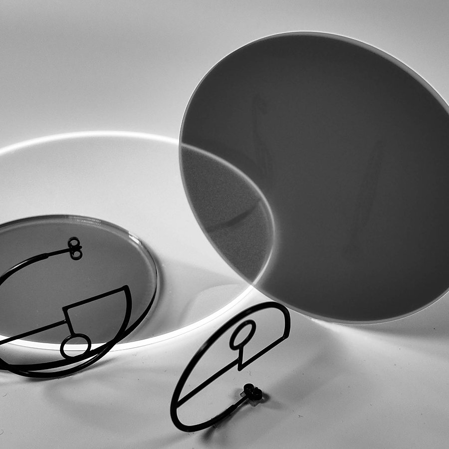 Black wire hoop earrings with a keyhole-like circle, beside translucent discs