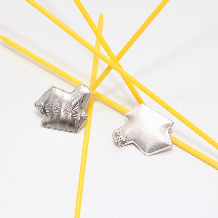 Angular silver stud earrings, one turned to show its smooth back and post