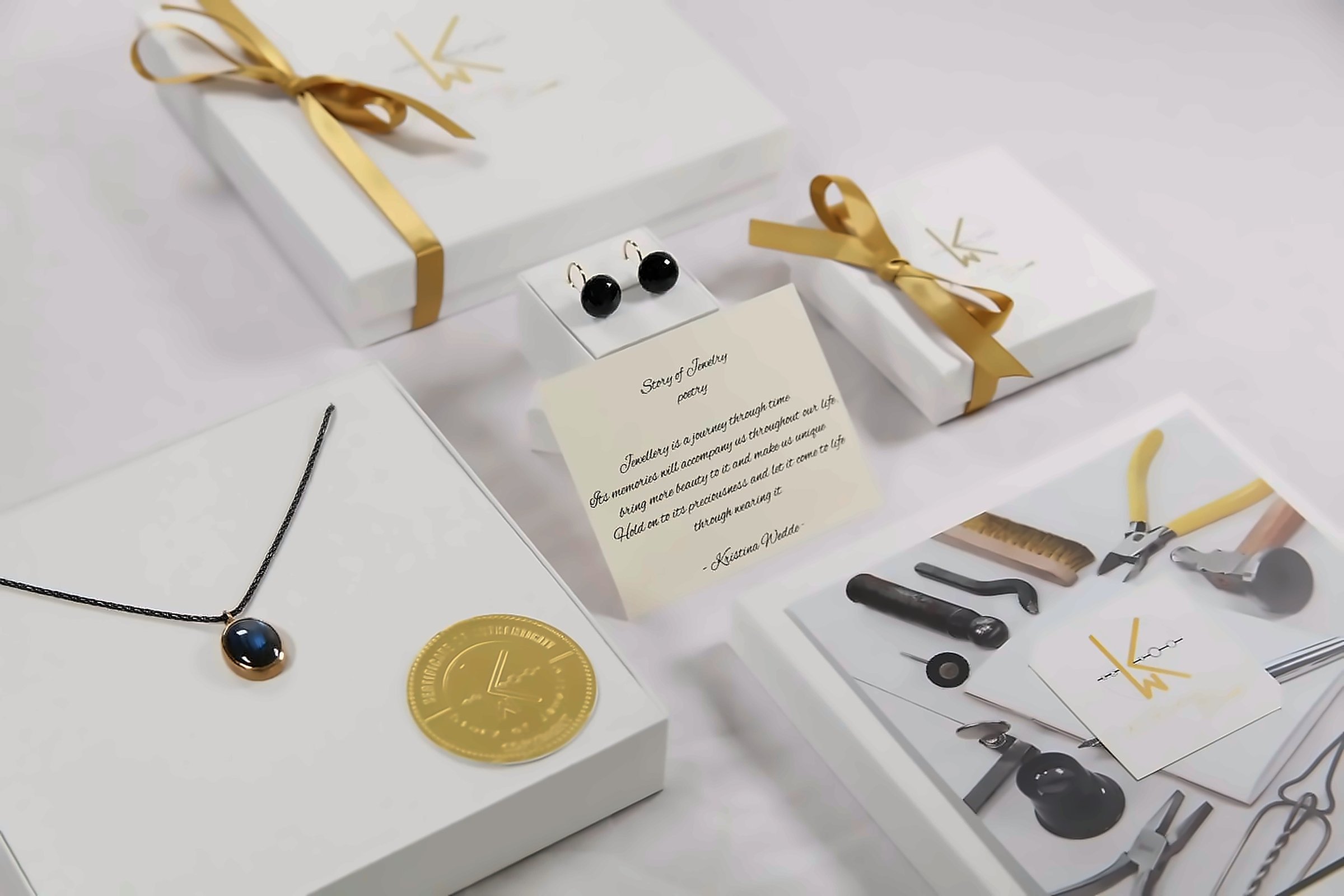 White gift boxes with gold ribbons, the poem card, a pendant and jeweller’s tools